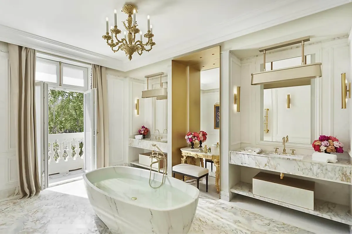 Spa bathroom with marble tub, chandelier, and floral table arrangements