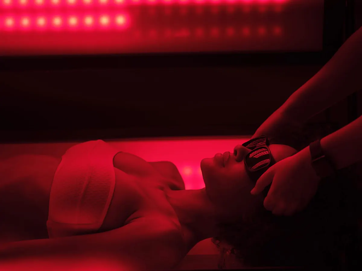 Red-light therapy room with hands on a patient during wellness treatment session