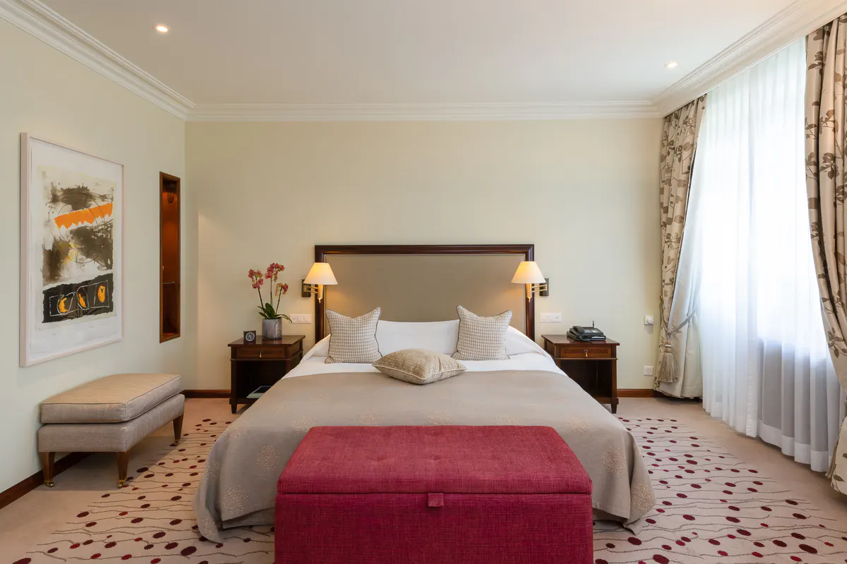 A luxury bedroom with a king bed, warm wood tones, large windows, and classic alpine decor