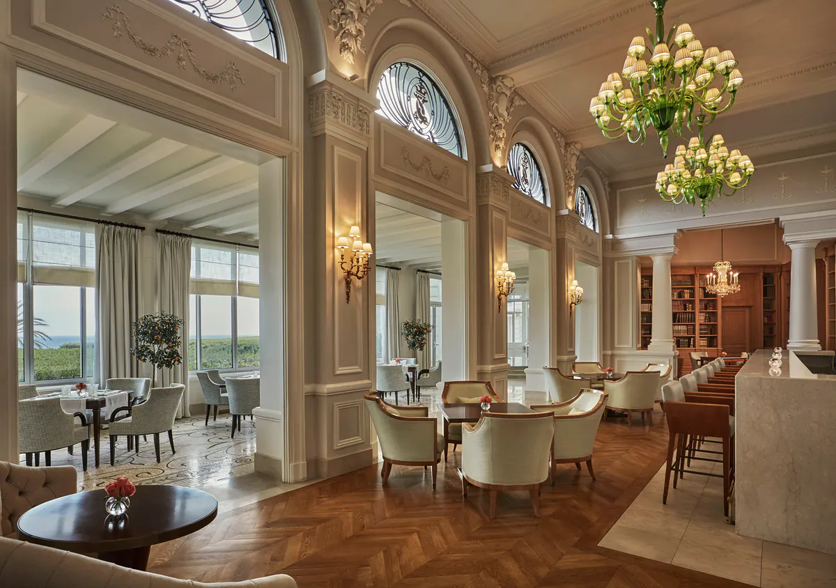 Formal dining room with gilded mirrors, crystal chandelier, and cream moldings