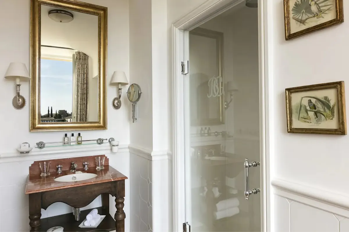 Bathroom vanity in natural wood with round mirror and framed botanical art