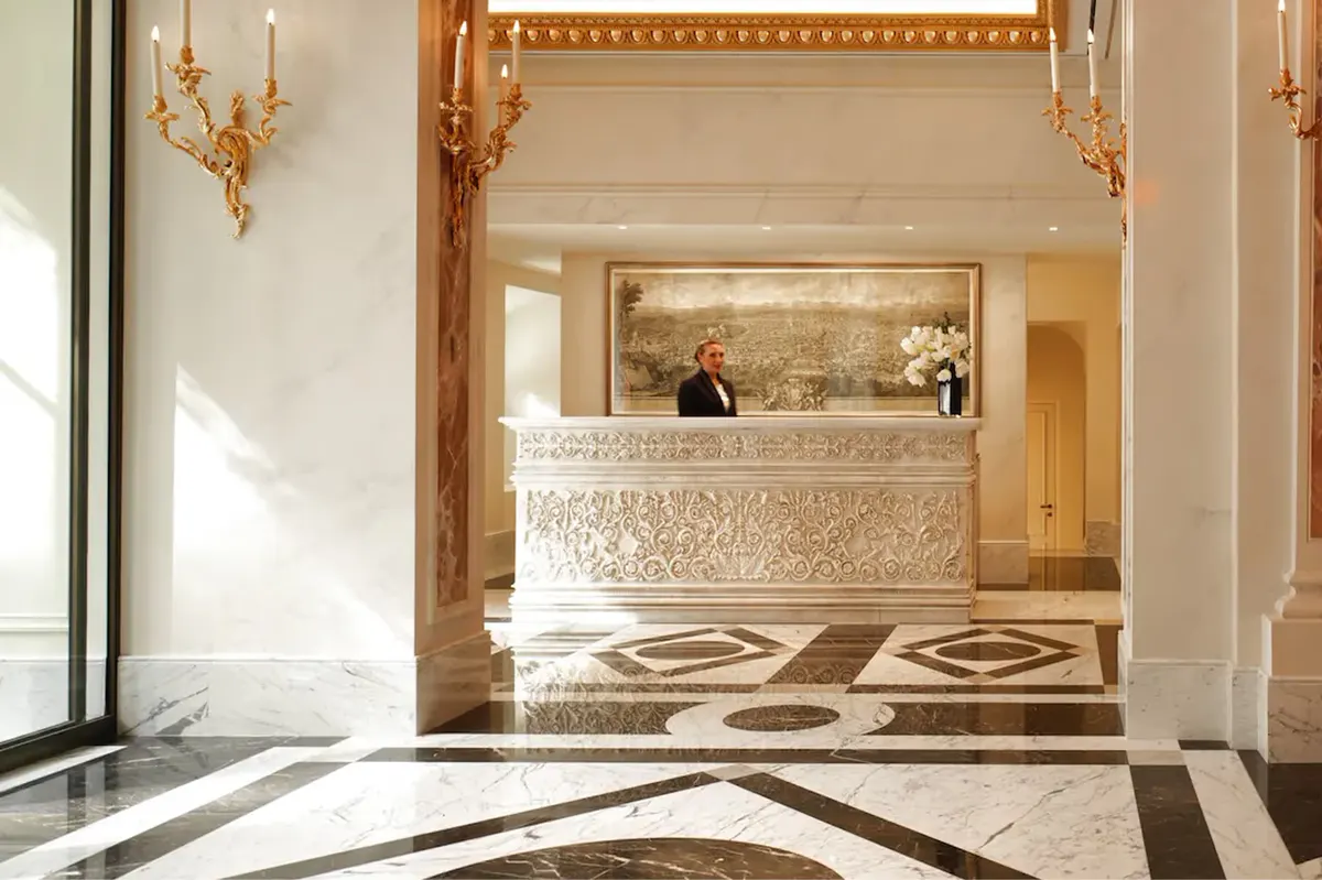The hotel lobby with an ornate ceiling, arched doorway to the reception desk, and terrazzo floor in gold tones