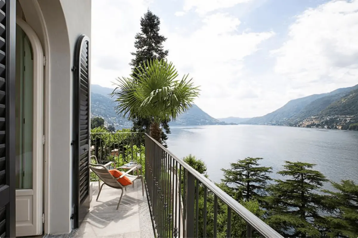 Terrace with shade tree and lounge chairs overlooking mountains and lake