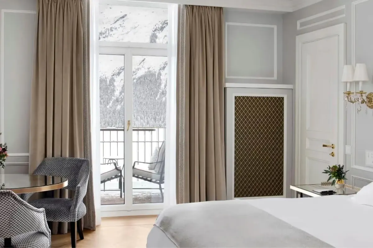 Bedroom with cream-colored walls, tall windows with valley views, tan curtains