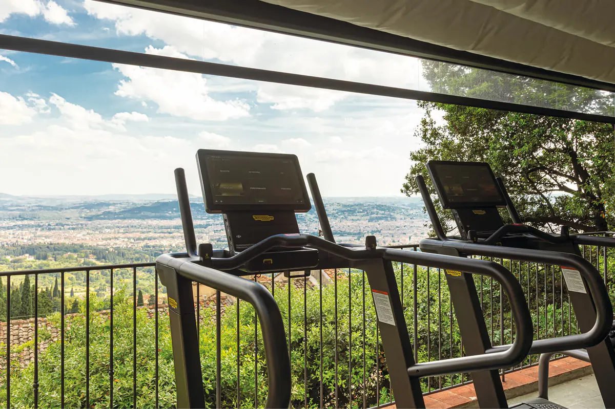 Exercise equipment on a terrace overlooking the Tuscany landscape with protective railings