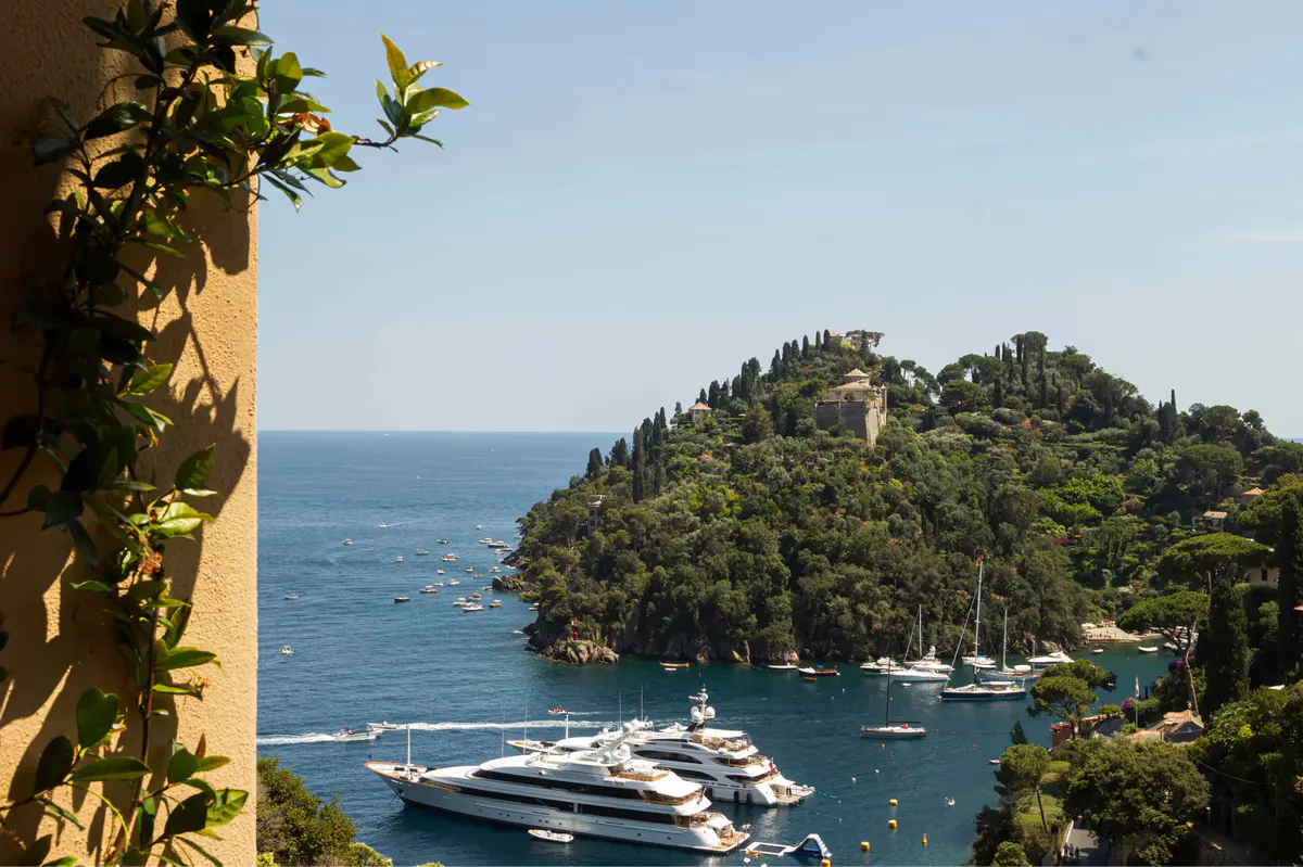 An oceanfront hotel cove with sailboats and tropical vegetation cascading to the water