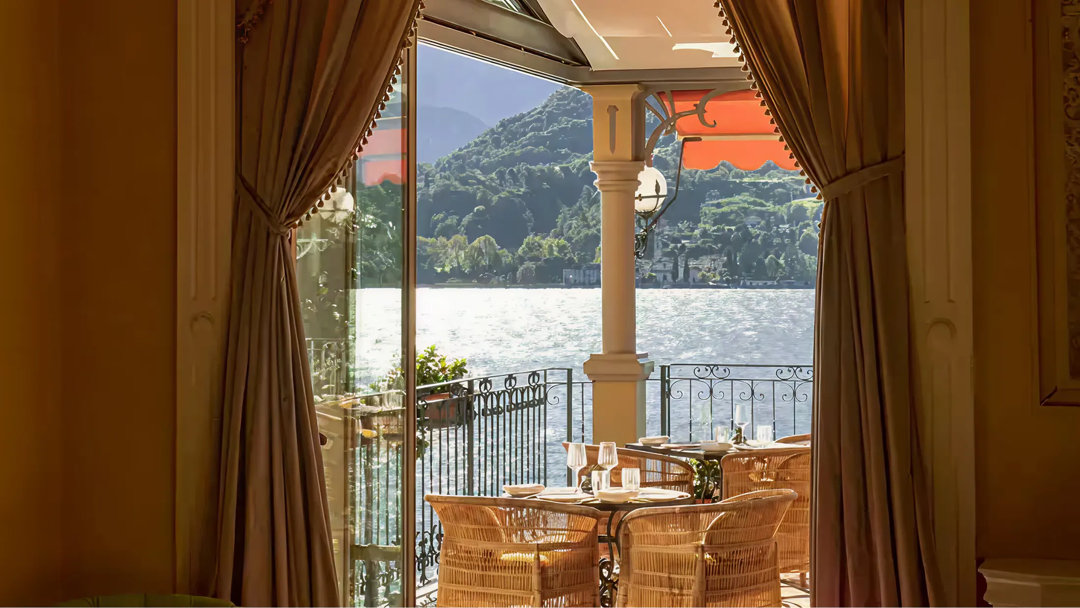 View from a suite terrace toward Lake Como framed by gold curtains and wood doors