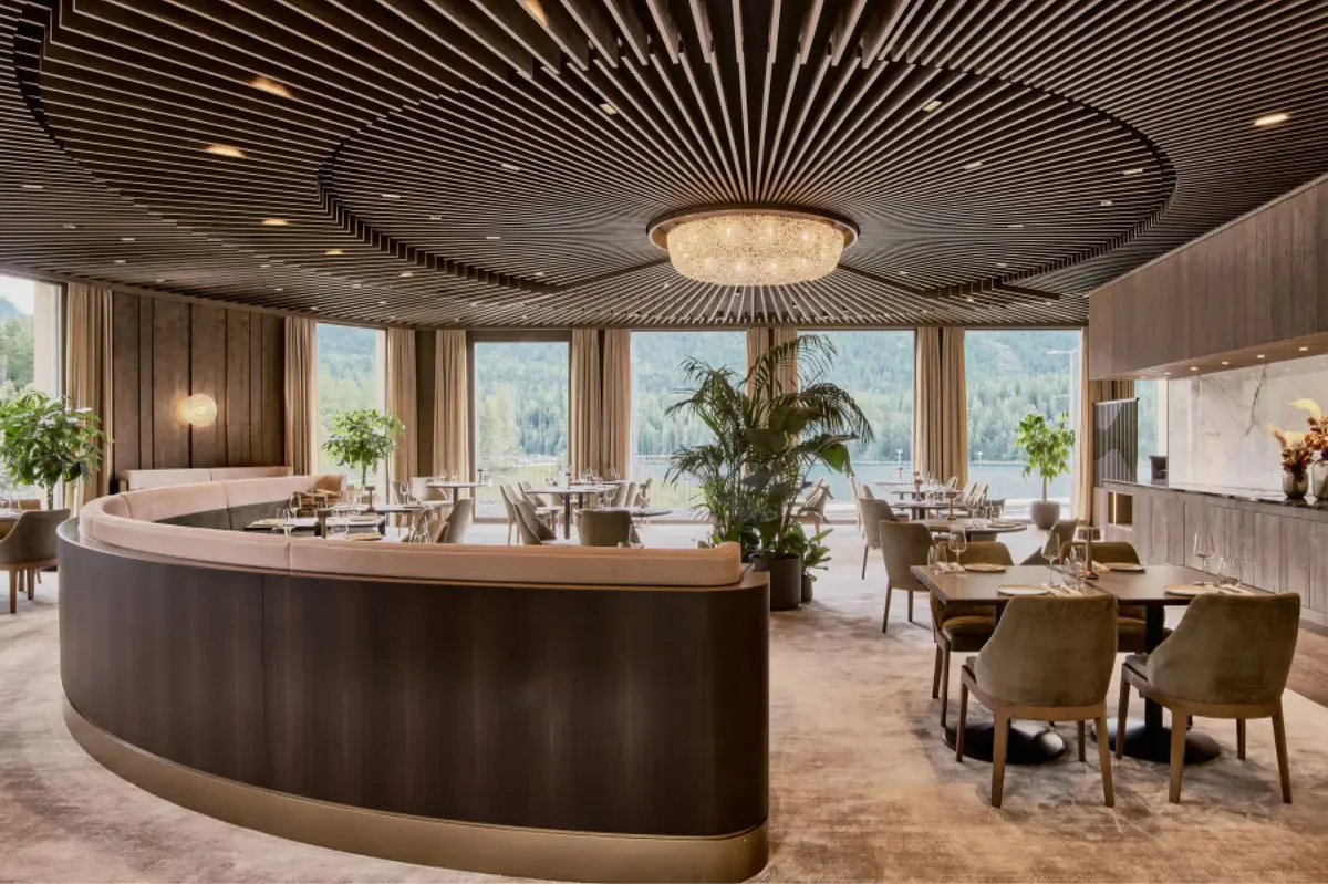 Modern dining space with curved dark wood bar, pendant lighting, and floor-to-ceiling windows