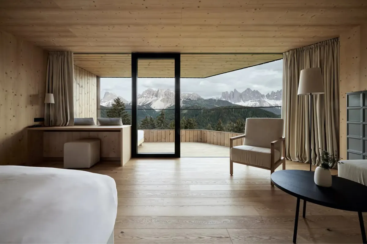 A guest suite with expansive glass doors opening onto a terrace with mountain views in daylight