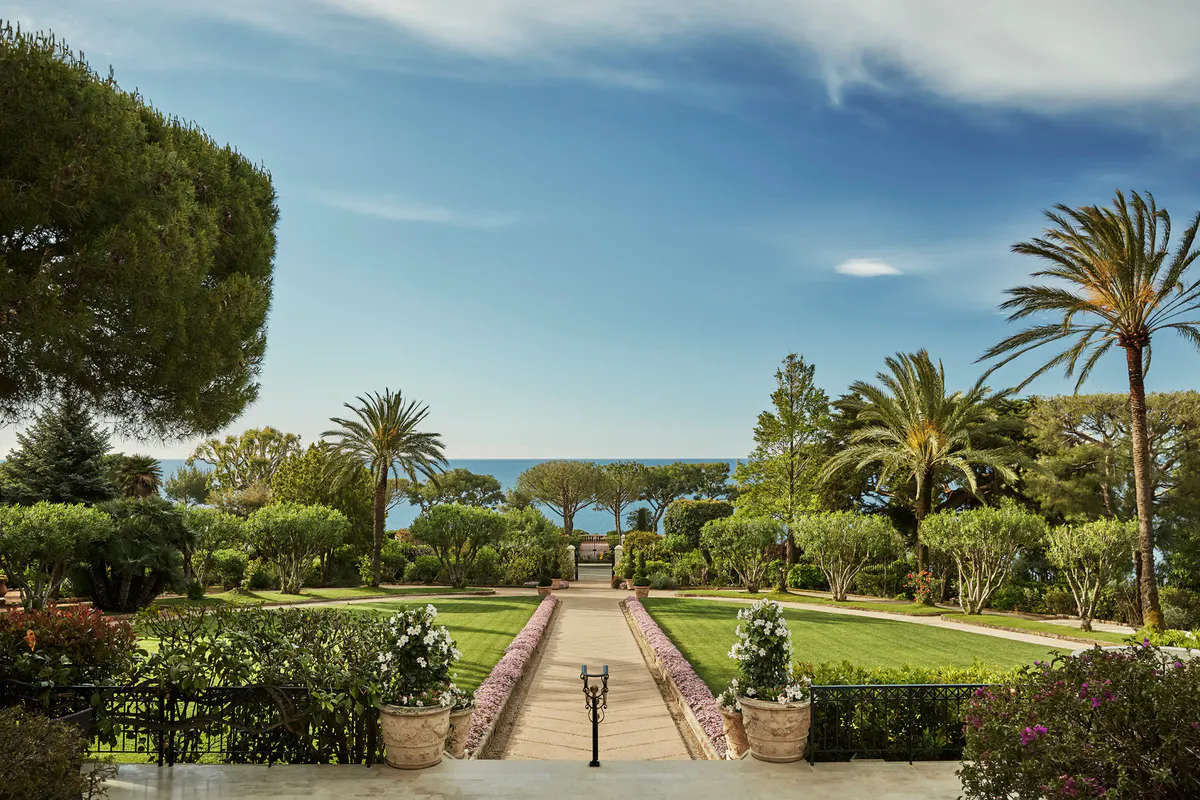 Palm trees and Mediterranean gardens with stone pathways and sea view