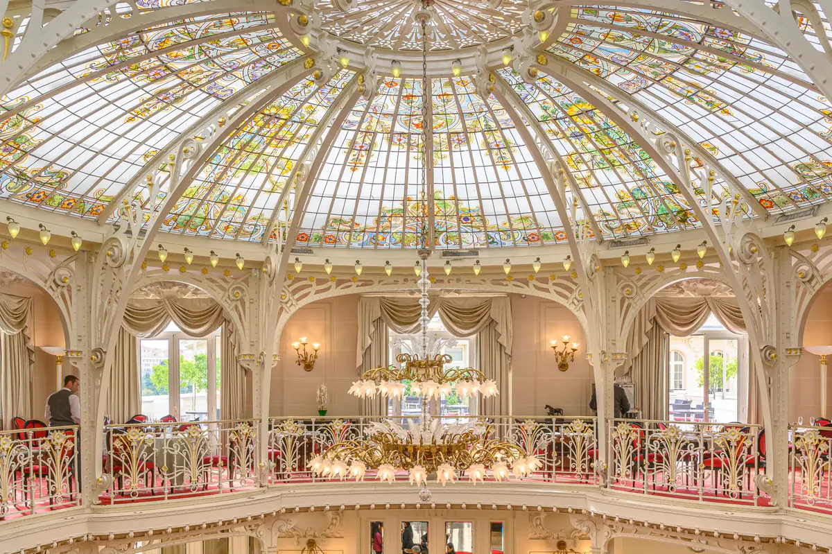 Historic glass-domed winter garden ballroom with cream and red upholstered seating