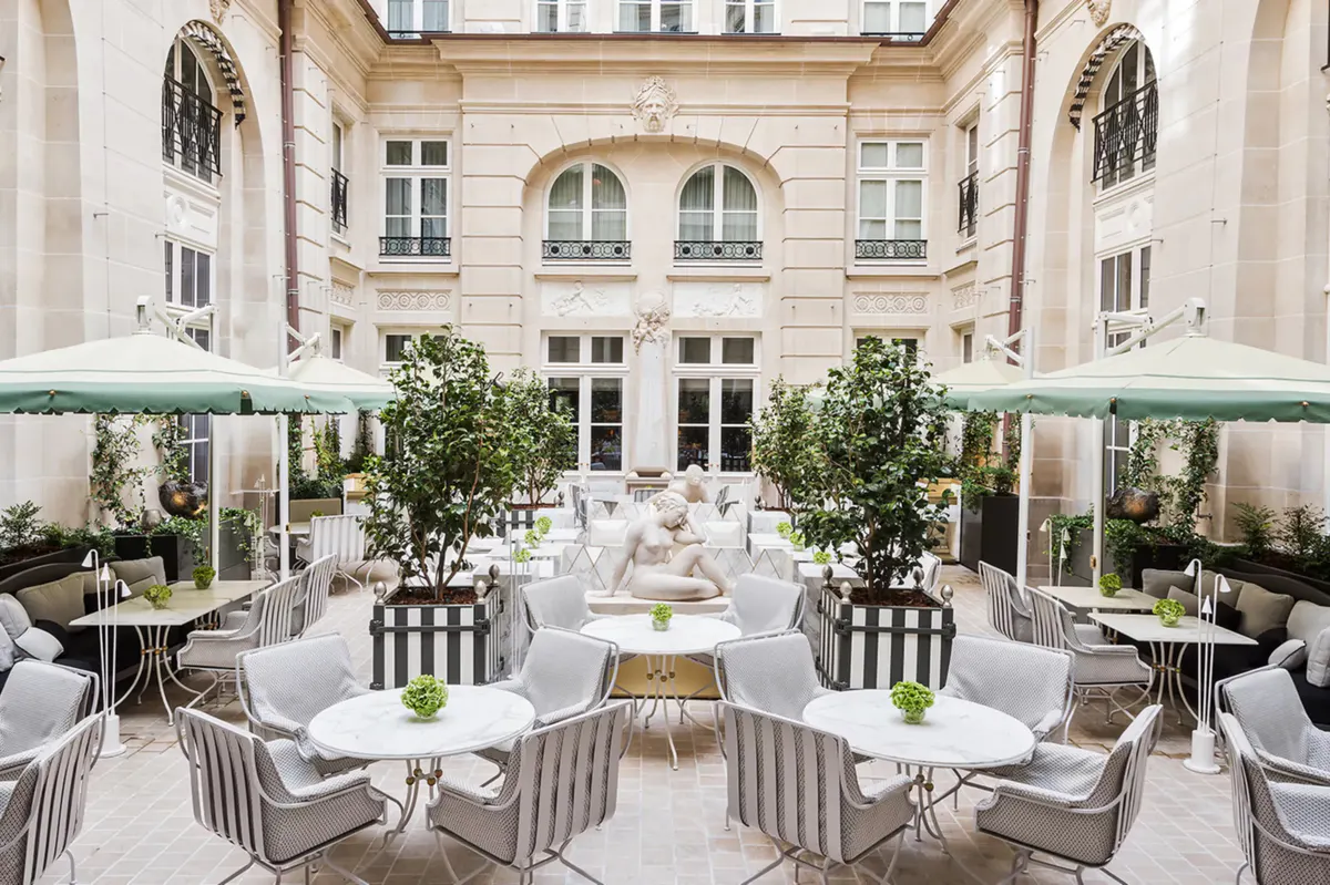 Courtyard terrace with white tables and striped chairs overlooking classical architecture