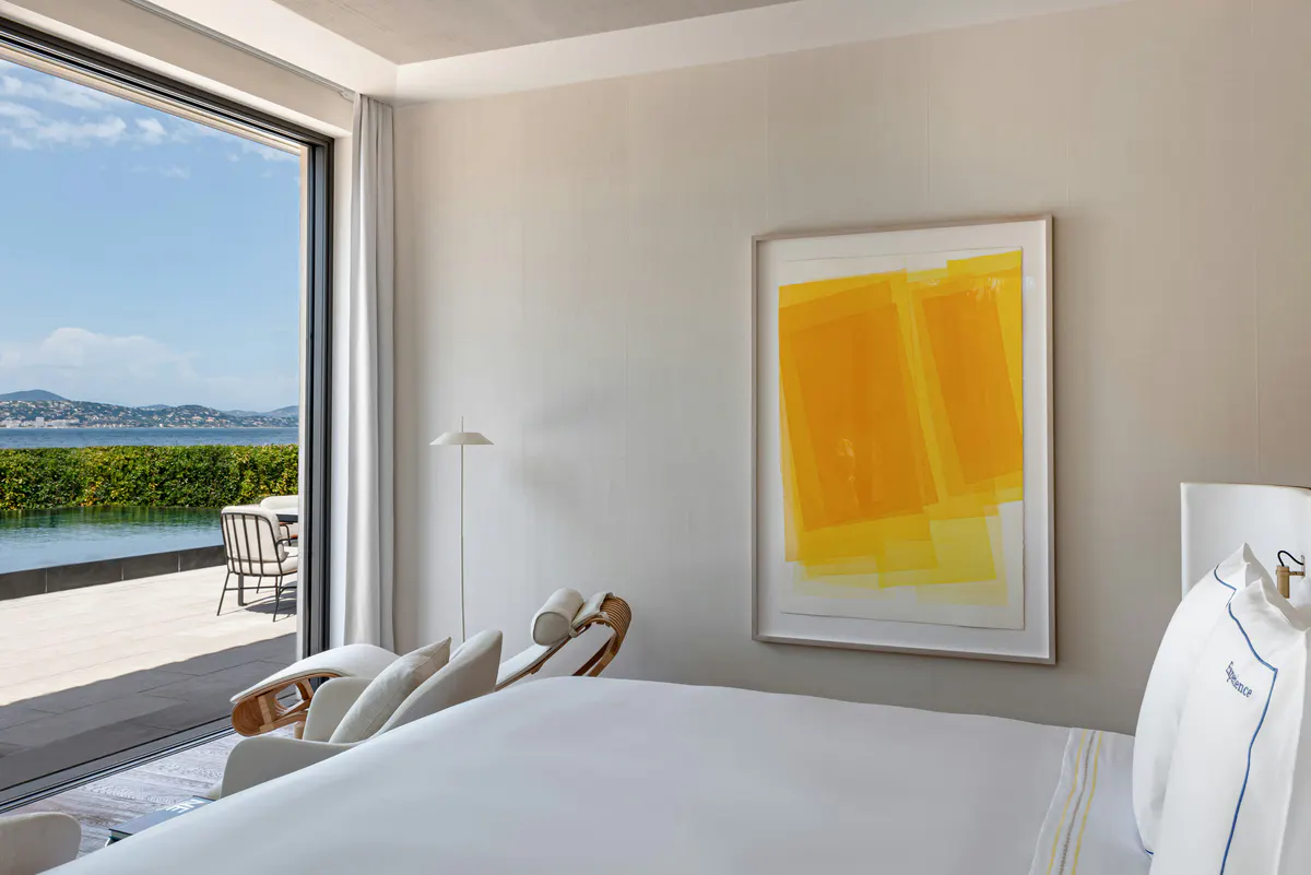 Bedroom corner with white bed and abstract yellow artwork