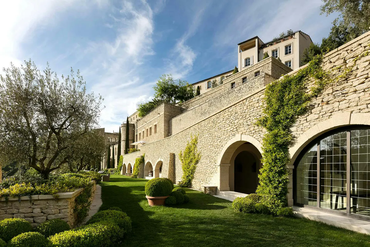 Stone archway opening to gardens with cypress and mountain vistas
