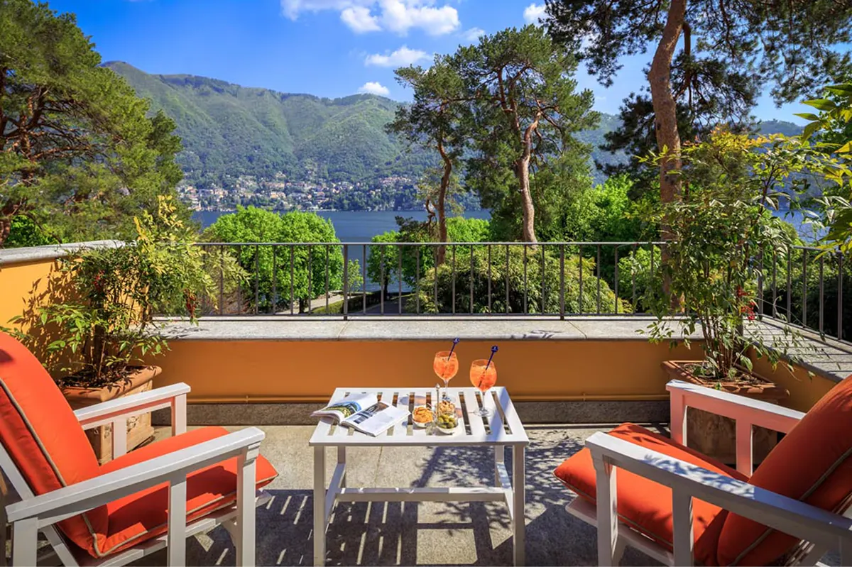 Waterfront terrace with coral cushioned chairs and panoramic lake and mountain views