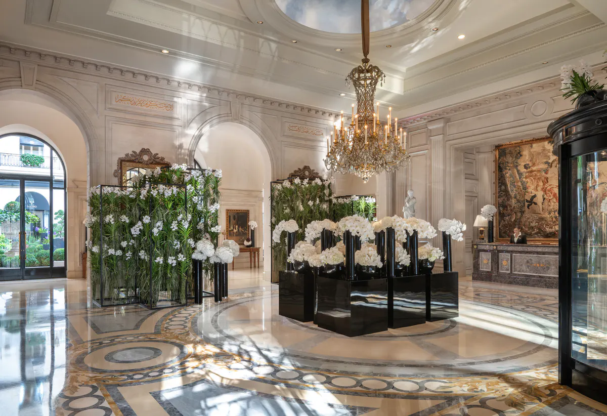 A bright lobby with cream arches, floral arrangements, and a marble floor pattern