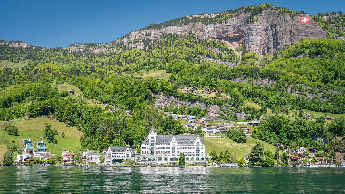 Hotel on lakeside with mountain ridge and Alpine slopes visible