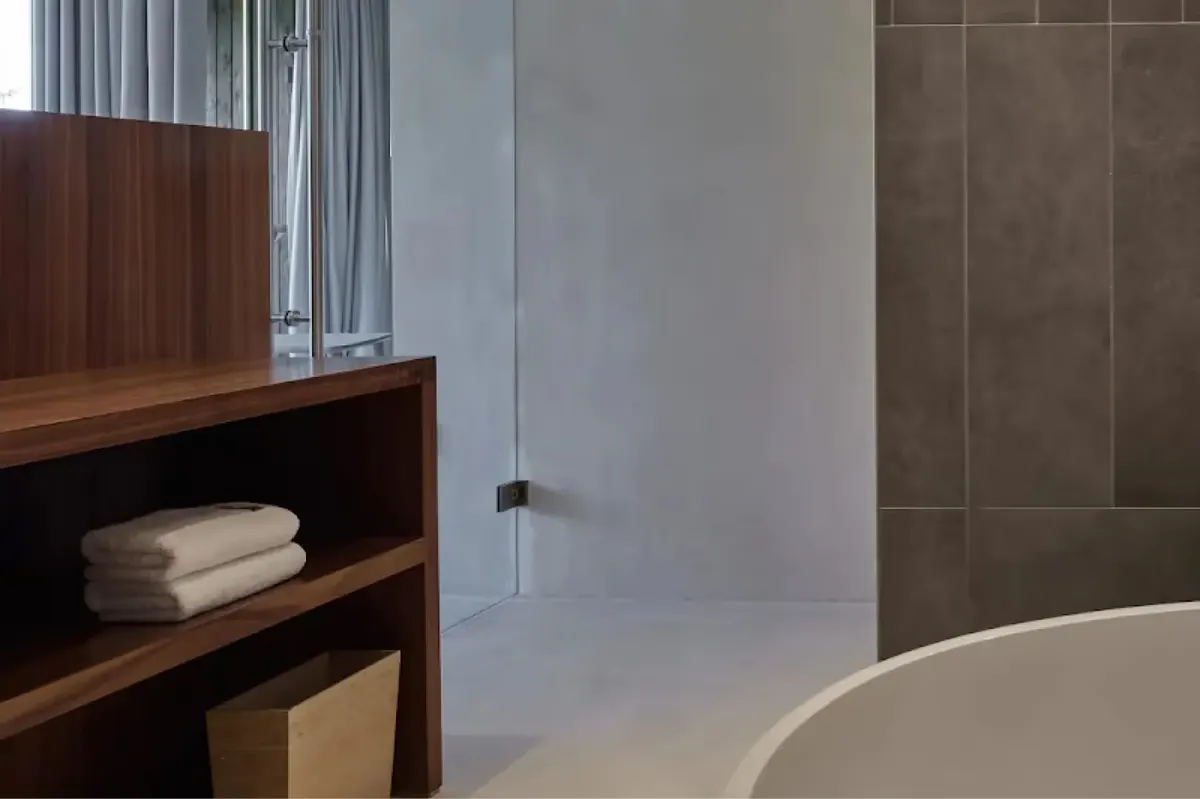 Bathroom with wood vanity, white sink, and frosted glass partition wall