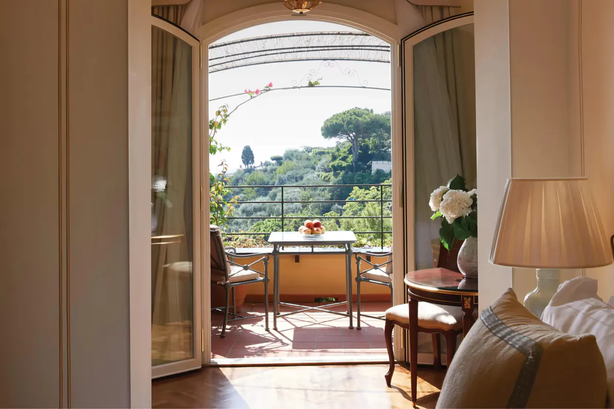 A suite living room with upholstered chair and ocean view from open glass doors