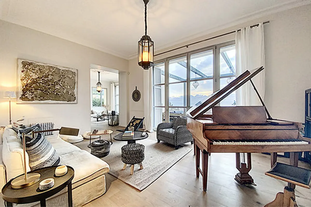 Living room with black piano, beige upholstered seating, and glass doors to sea-facing terrace