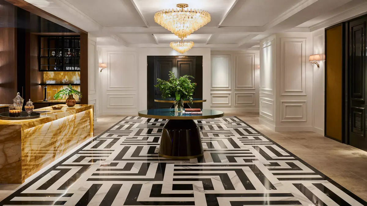 The lobby with black and white geometric flooring, crystal chandelier, and decorative plants
