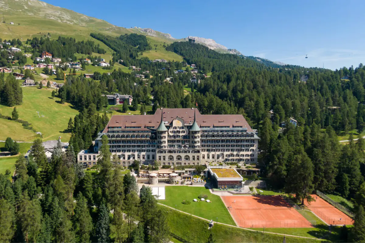 The hotel surrounded by meadows and forest with larch and pine trees across rolling terrain
