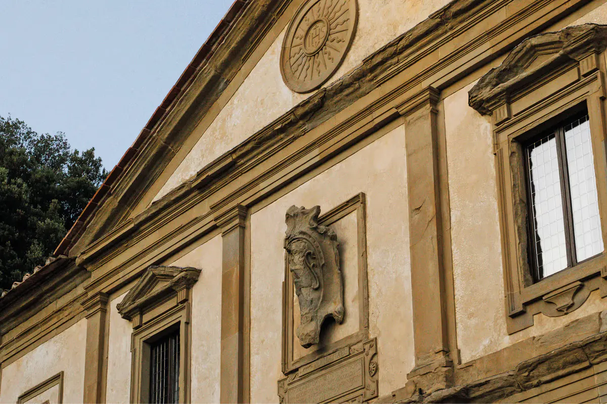 Stone facade with carved lion head, sunlit moldings, arched windows, and classical architectural details