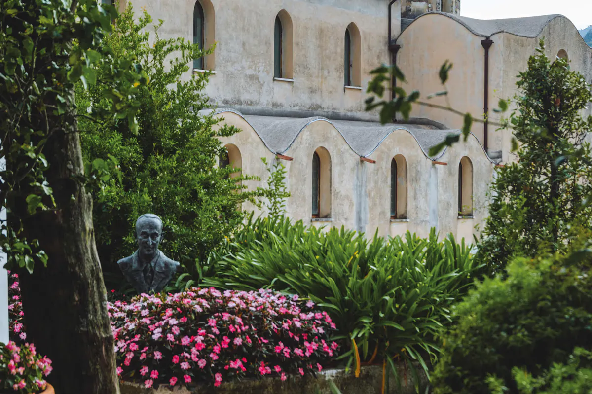 Mediterranean palace exterior with flowering magenta plants and stone balcony overlooking coast
