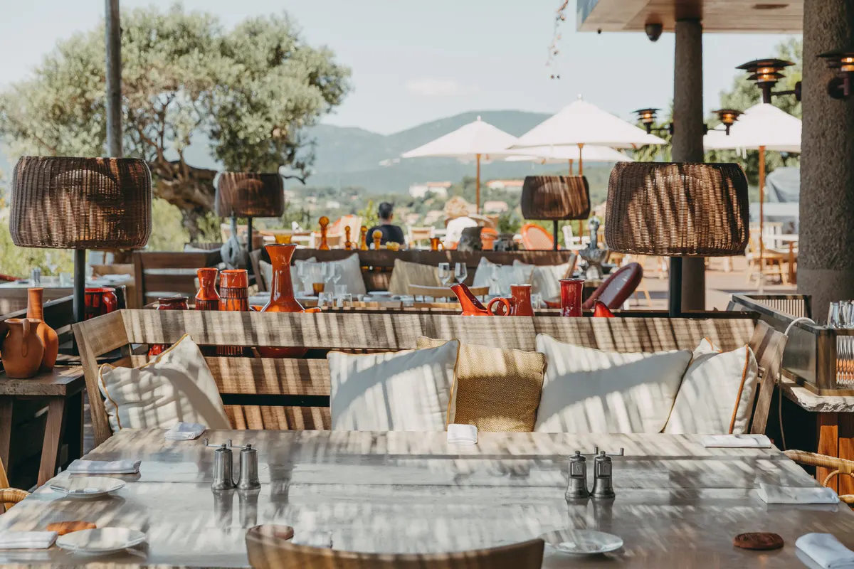 Outdoor dining area with striped chairs and mountain views beyond
