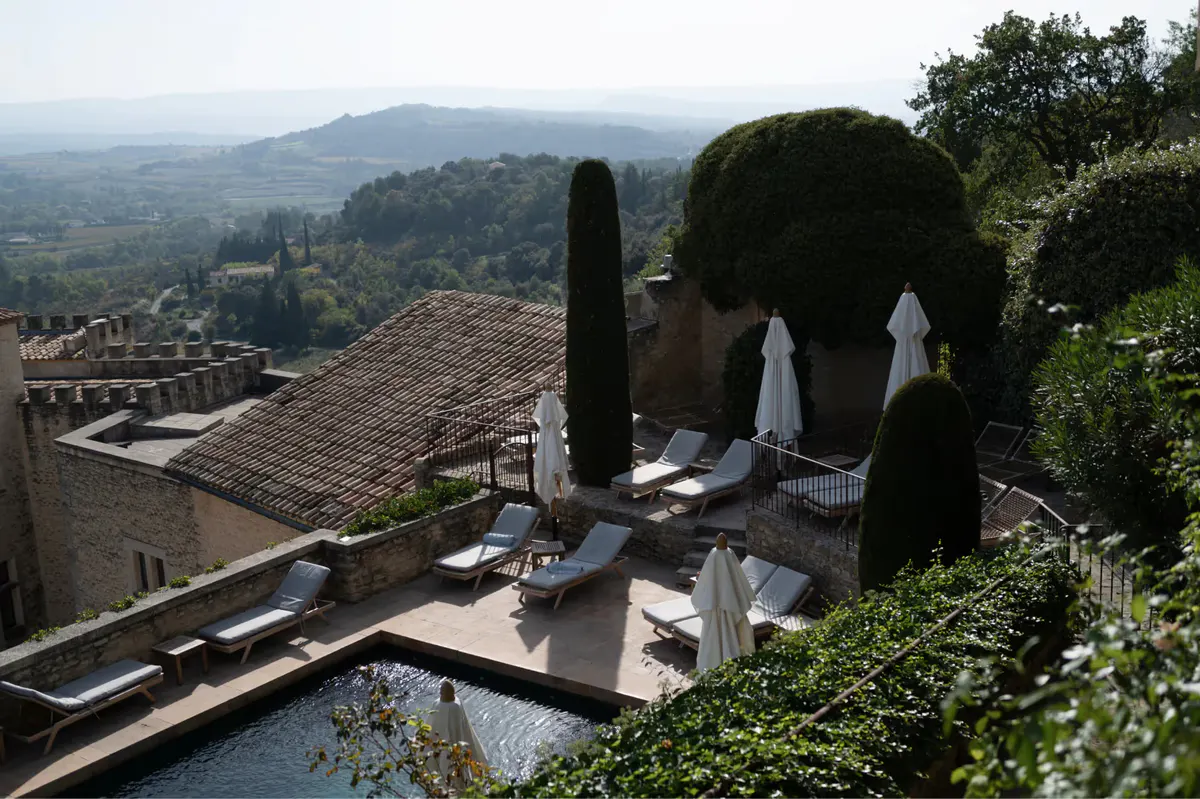 The pool terrace with cypress trees, umbrellas, and panoramic views of the Provençal countryside
