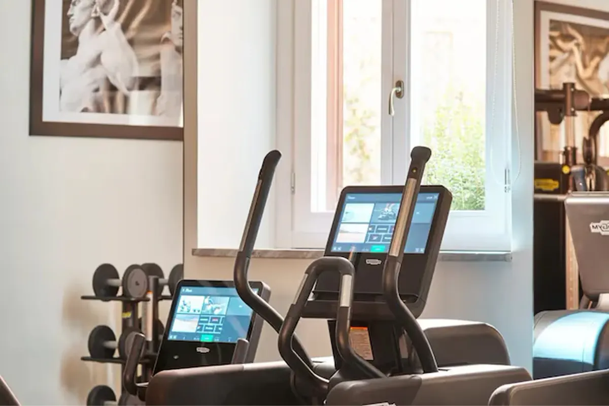 A fitness studio with multiple stationary bikes, screens, and windows looking onto an interior courtyard