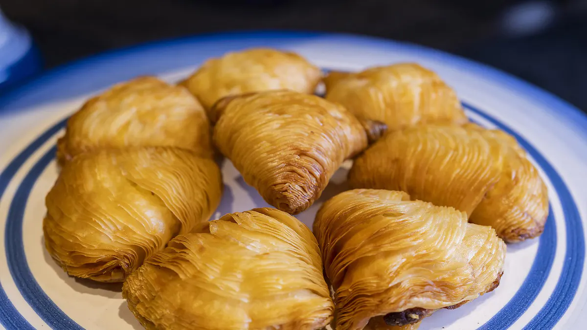 Golden pastries on a ceramic plate with blue-and-white trim, traditional Italian desserts