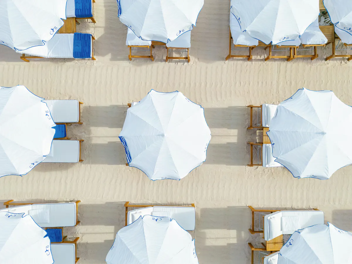 Aerial view of striped umbrellas and sunbeds in organized rows