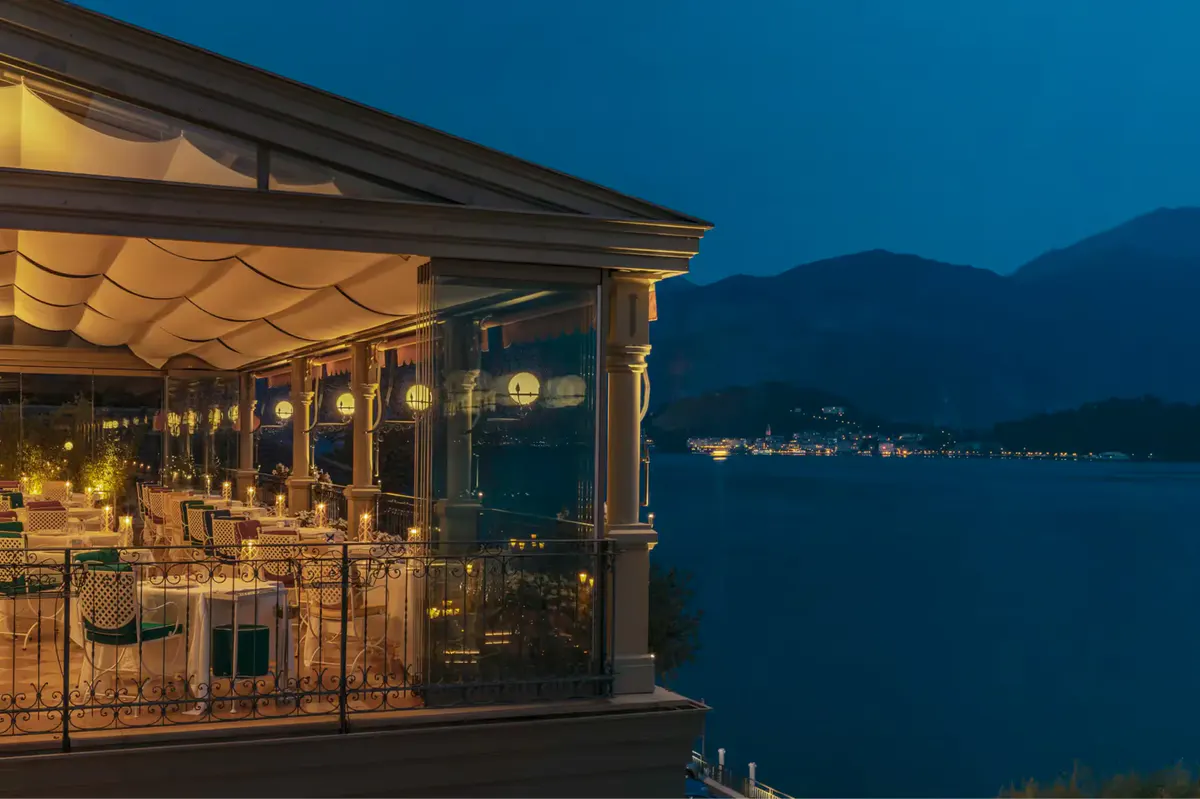 Lit restaurant pavilion reflected on dark water at twilight