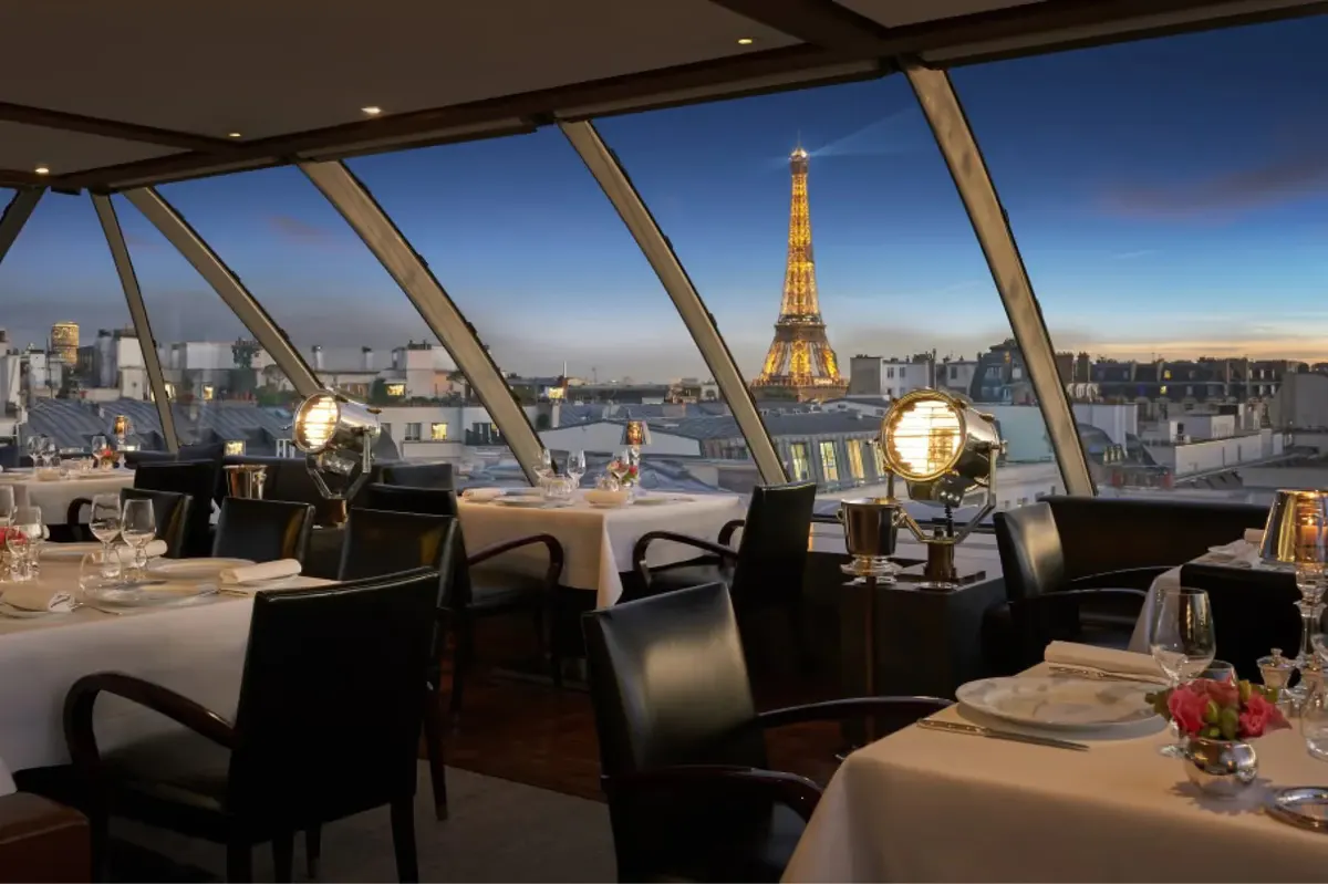 Rooftop terrace at night with candles, white linens, and Paris cityscape including the Eiffel Tower