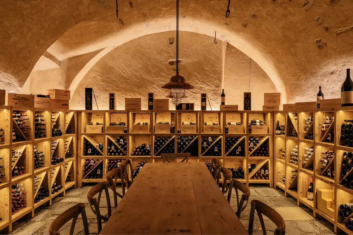 Underground wine cellar with wooden chairs lining curved stone walls