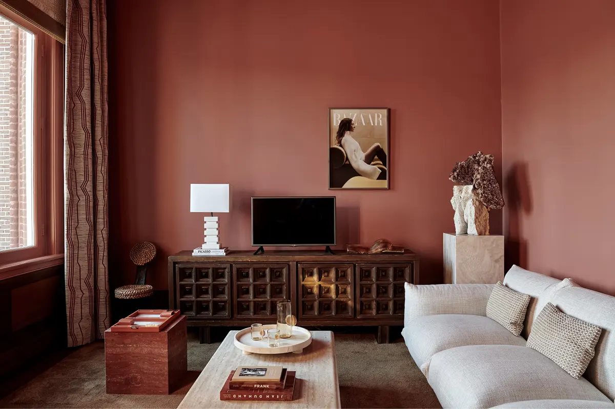 Suite sitting area with terracotta accent wall, cream upholstered seating, and entertainment console