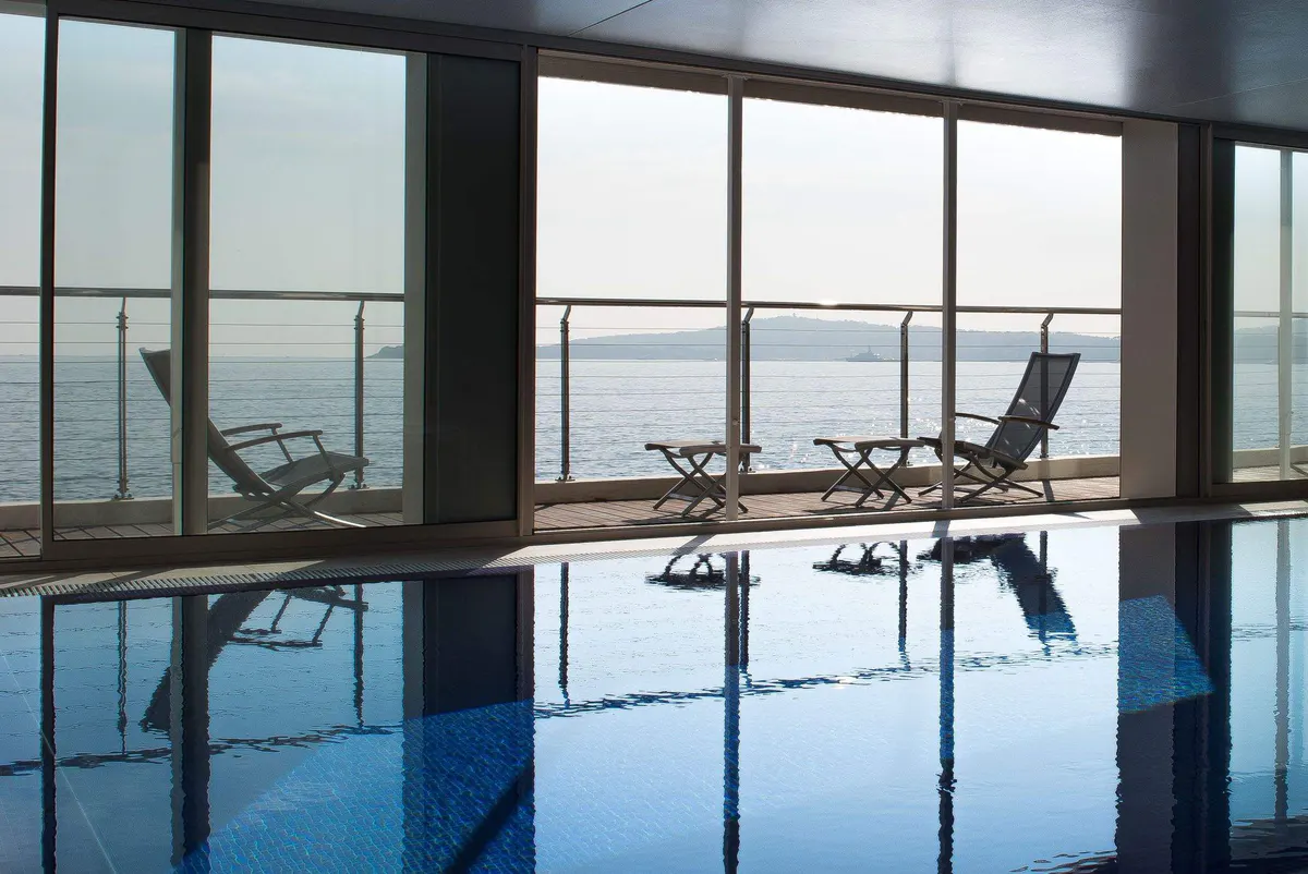 An indoor pool with floor-to-ceiling windows and sea views