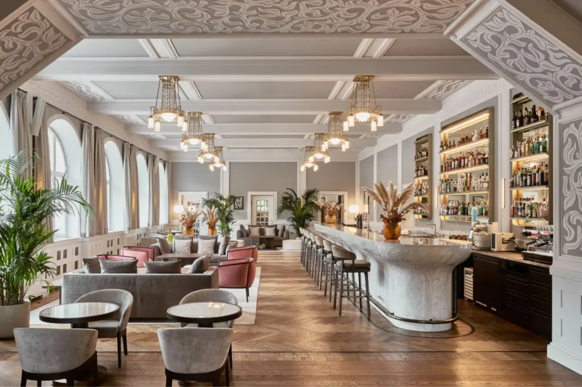 Elegant dining room with ornate ceiling, hanging pendants, built-in shelving, and round tables