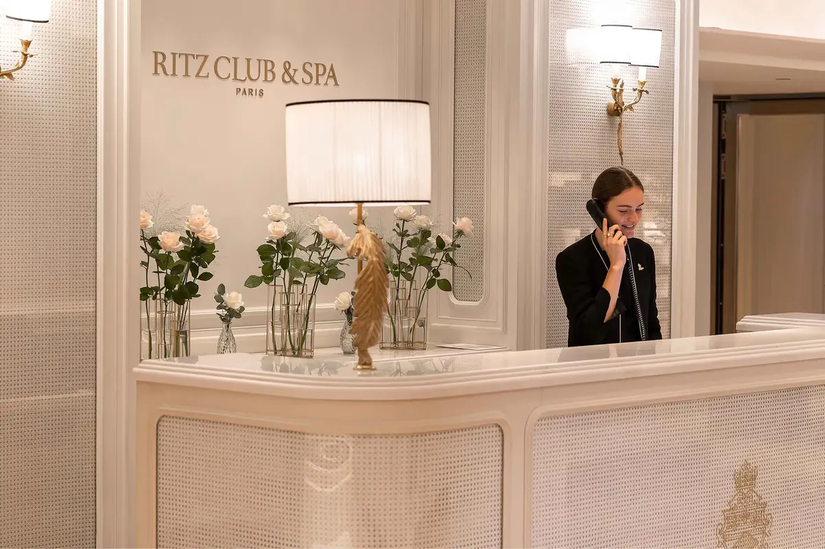 The Ritz Club & Spa reception desk with white marble and fresh floral arrangement