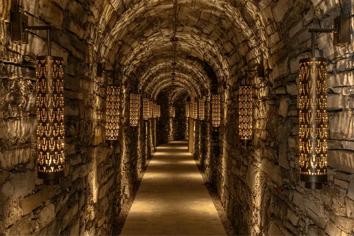A tunnel passage with illuminated stone walls and arched brick ceiling