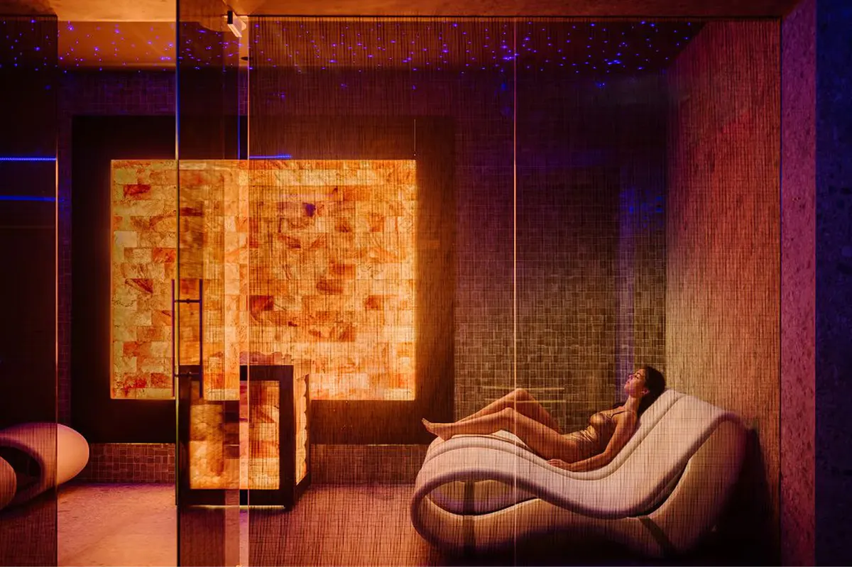 A lounge with warm orange-amber tones, sculptural furniture, and mood lighting
