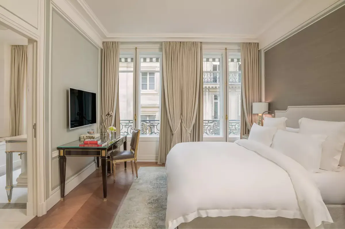 Bright room with white bed, beige walls, tall windows, and hardwood floors