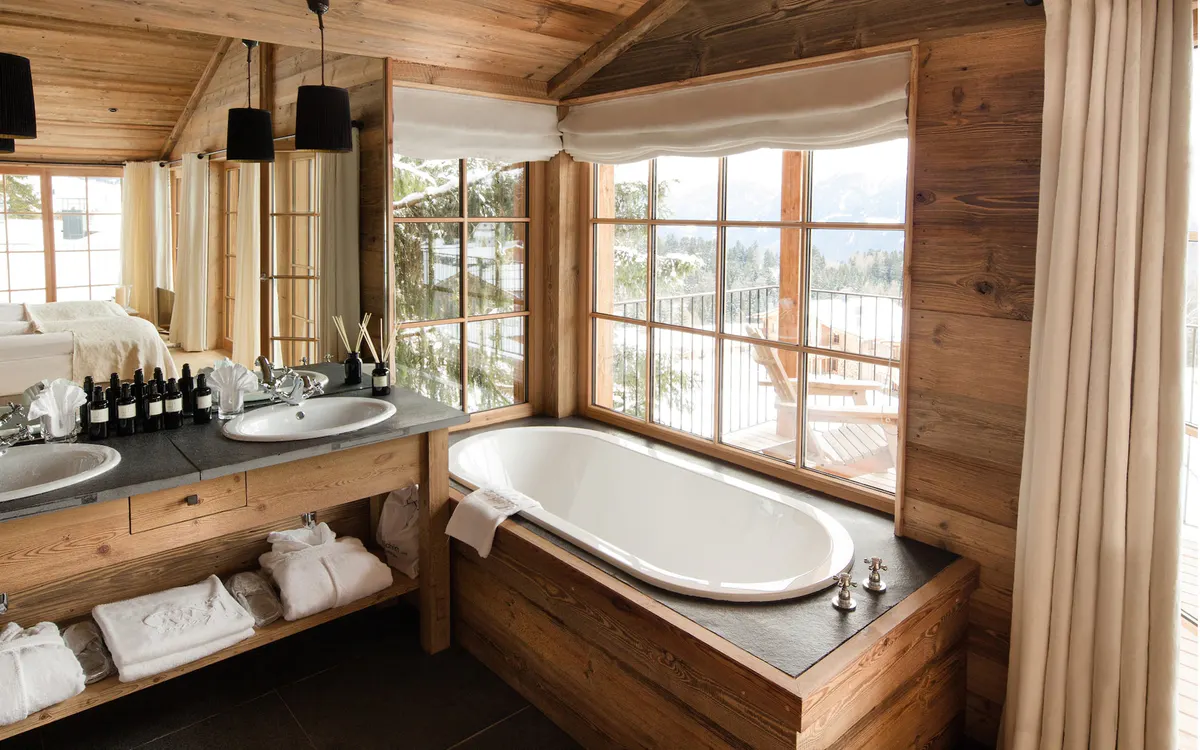 Wooden bathroom with a large soaking tub beside a sink vanity near windows