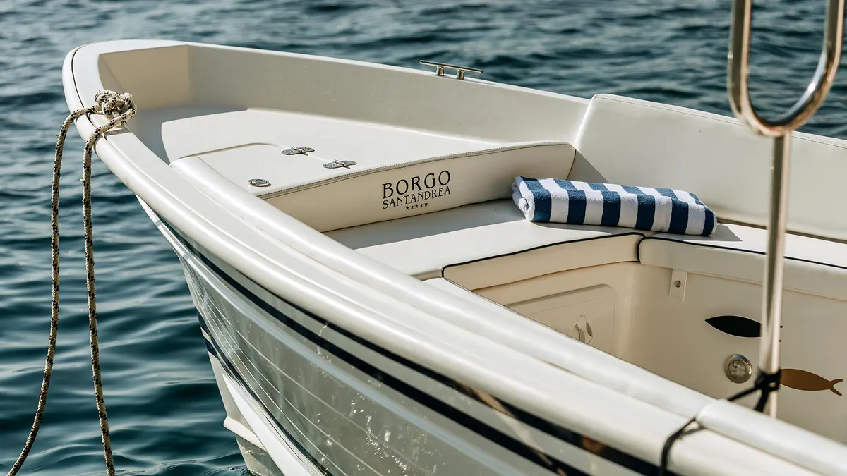 White boat moored in clear water with striped cushions and rope detail