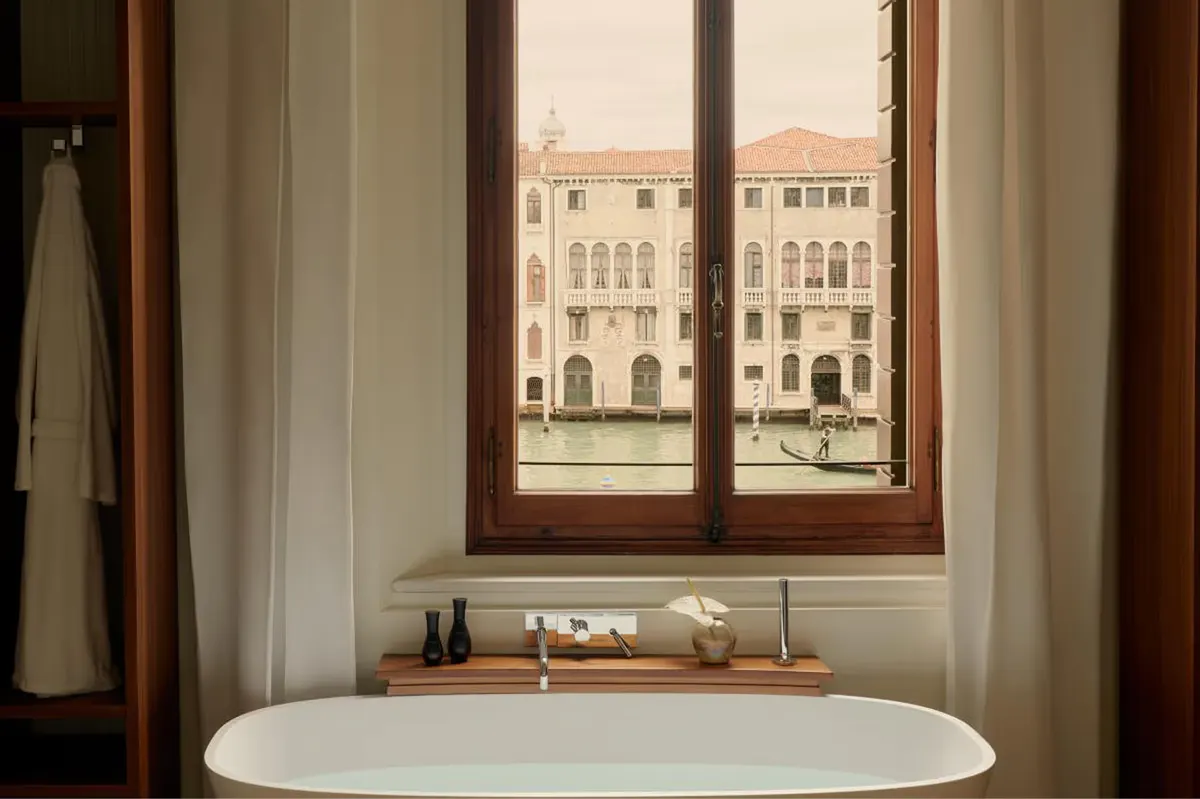 A soaking tub positioned at a tall window overlooking the Grand Canal with wooden trim framing the view