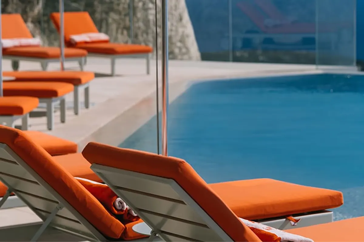 Orange lounge chair by pool with ocean backdrop