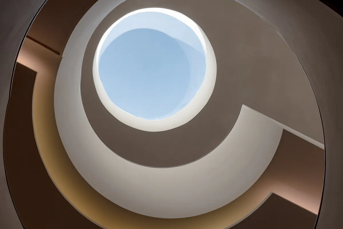 Architectural spiral staircase viewed from above with circular skylight opening