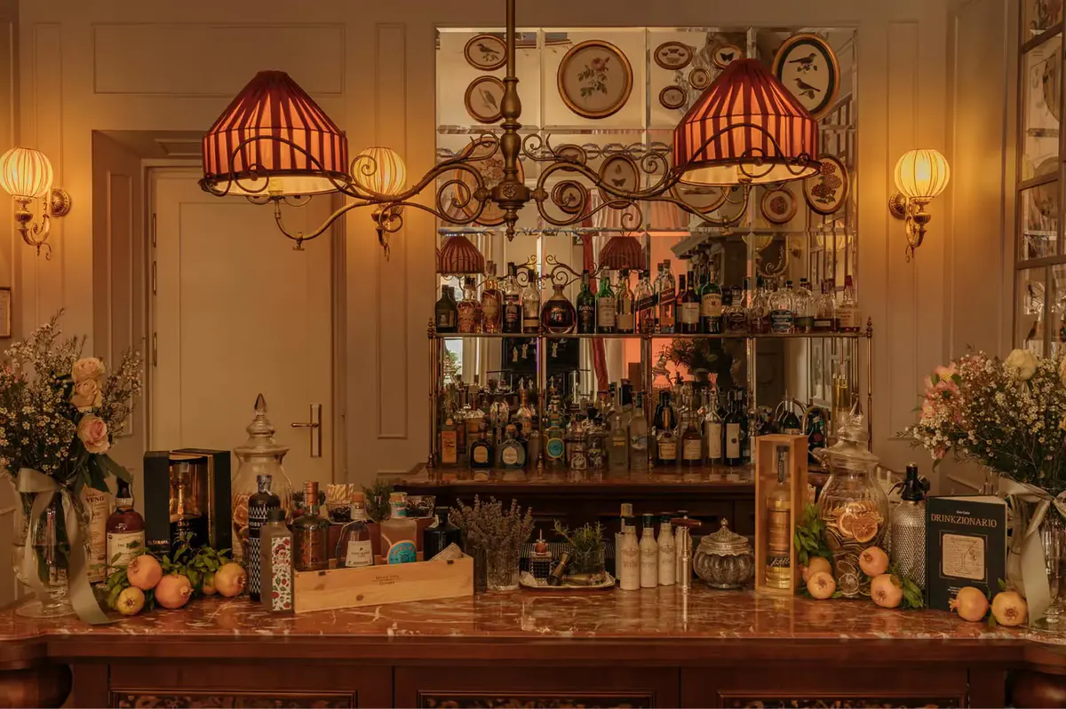 A bar counter with ornate wall plates, stemware, and tiered bottle display