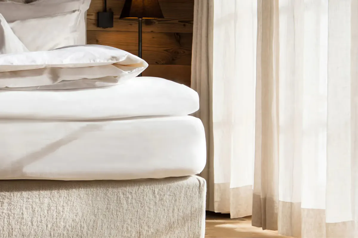 Close-up of white pillows and bedding on a wooden platform bed